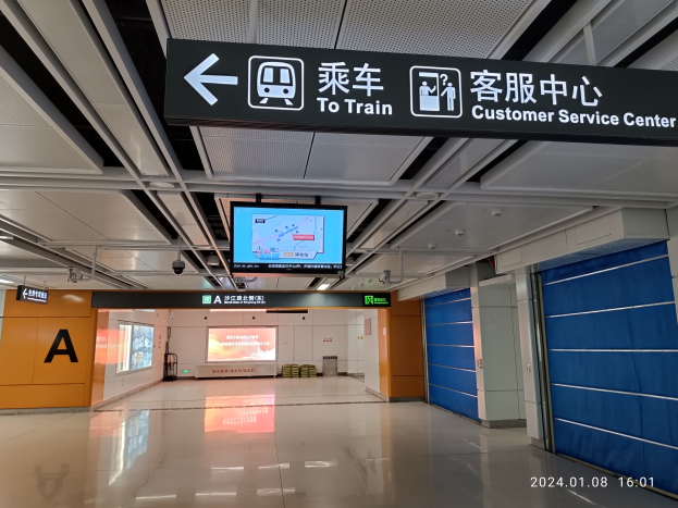 Innensicht eines Bahnhofs mit einem "Zum Zug Kundenservice-Zentrum"-Schild oben, sichtbarem Boden, Türen auf der rechten Seite, Deckenbretter, ein zentraler Bildschirm und ein Wasserzeichen unten rechts.