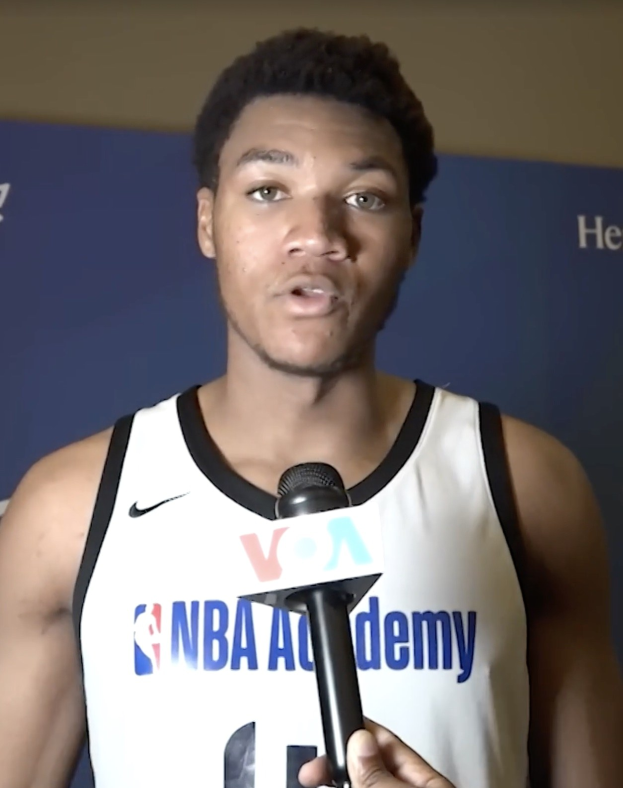 Ein Mann in einem wei├čem Tanktop mit einem Mikrofon spricht mit der Medien bei der NBA All-Star Game 2019, mit einem Banner und einer Wand im Hintergrund.