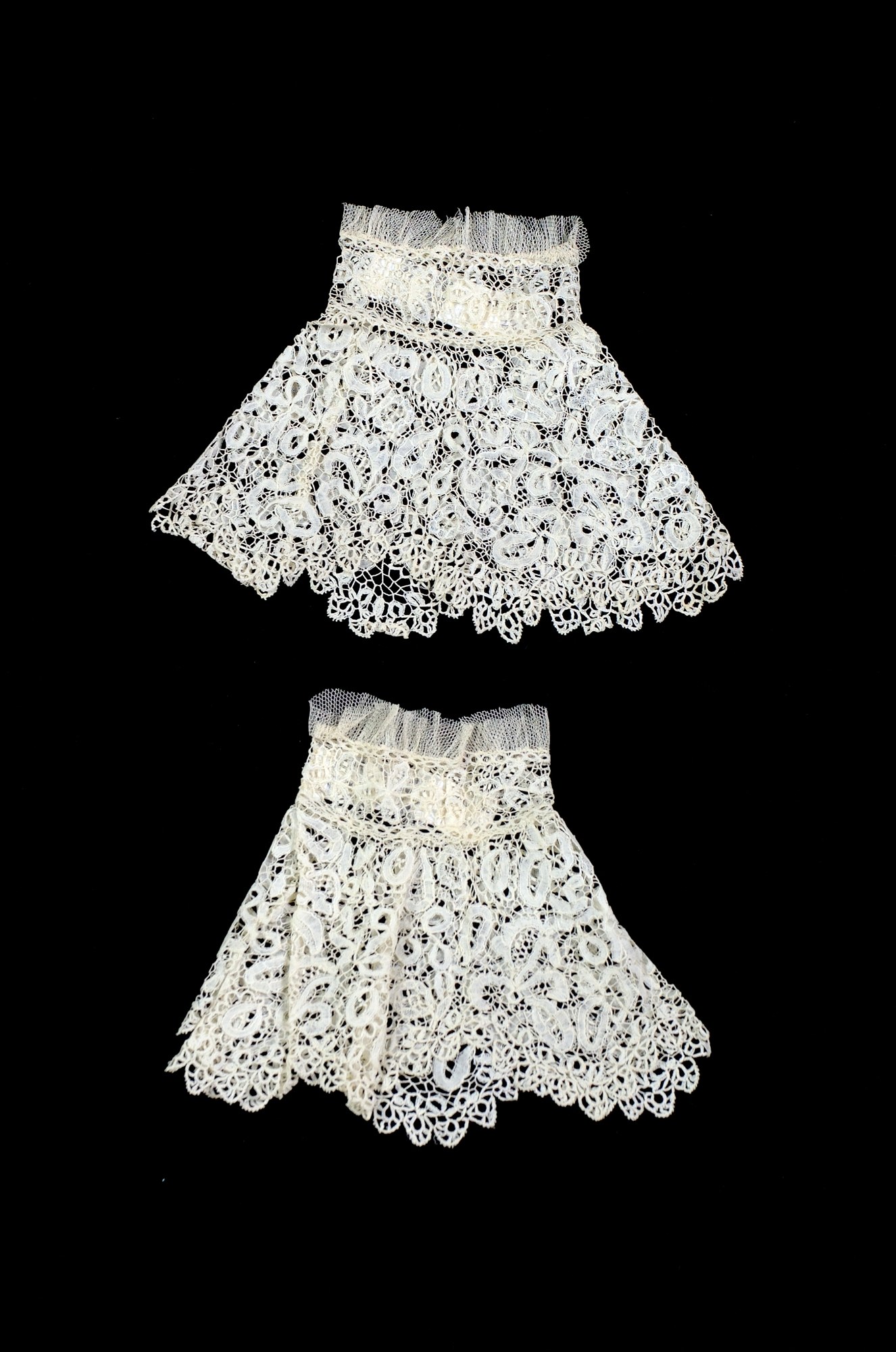 Zwei weiße Spitzenröcke mit zarten Mustern auf schwarzem Hintergrund.