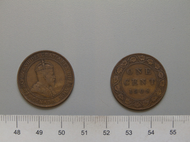 Zwei US-Ein-Cent-Münzen nebeneinander auf einem Lineal auf einer weißen Oberfläche.