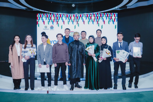 Gruppe von Menschen auf einer Bühne mit Blumensträußen und Urkunden, vor dem Hintergrund 'Jugend-Solar-Awards 2019'.