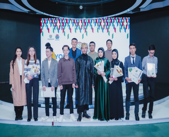 Gruppe von Menschen auf einer Bühne mit Blumensträußen und Urkunden, vor dem Hintergrund 'Jugend-Solar-Awards 2019'.