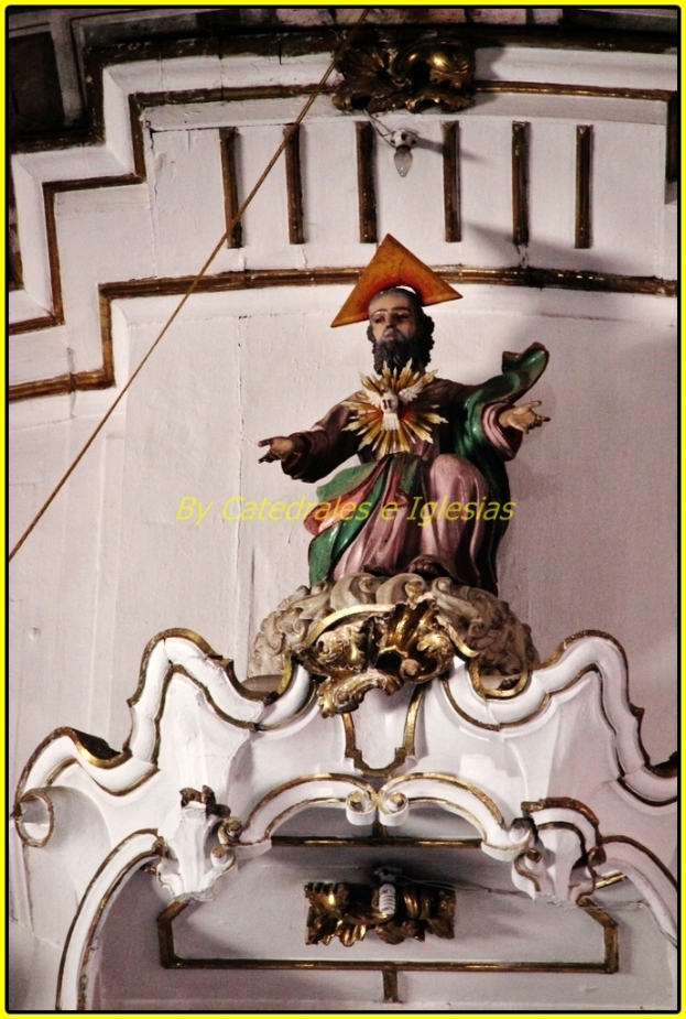 Eine Skulptur steht im Vordergrund mit einer Wand dahinter, die ein Kabel auf der linken und oberen Seite und eine Glühbirne an der Spitze der Wand zeigt.