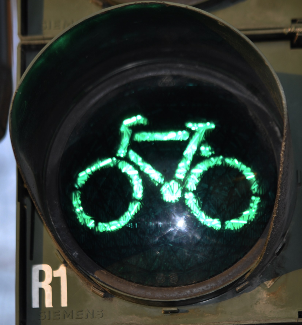 Grüne Ampel mit Fahrradsymbol, beleuchtet an einer Wand im Hintergrund.