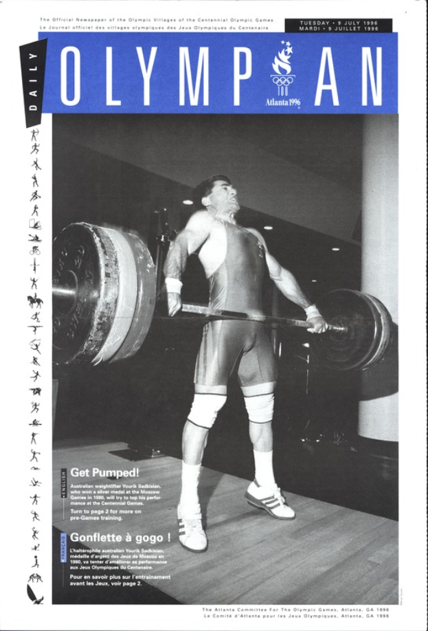 Ein Schwarz-Weiß-Foto eines Mannes, der eine Hantel stemmt, der eine Gewichtheber-Ausrüstung trägt, mit den Worten "Olympian Magazine" darüber geschrieben.