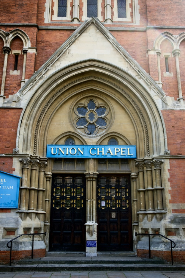 Eine große, historische Kirche in London mit zahlreichen Fenstern an den Wänden und zwei Türen am Eingang.