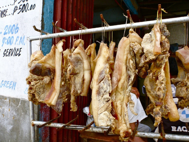 Fleisch an einem Ständer mit einer Person dahinter und eine Wand mit Text auf der linken Seite.