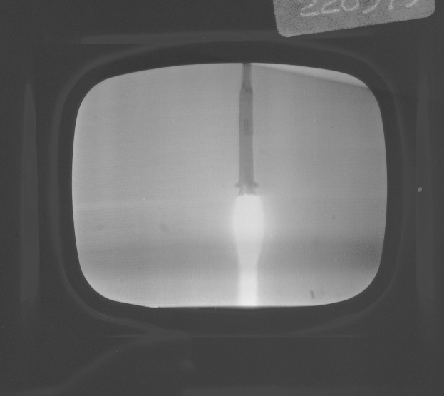 Schwarzes und weißes Foto eines Fernseherbildschirms mit einer Raketenstartszene durch das Fenster, mit Text oben.