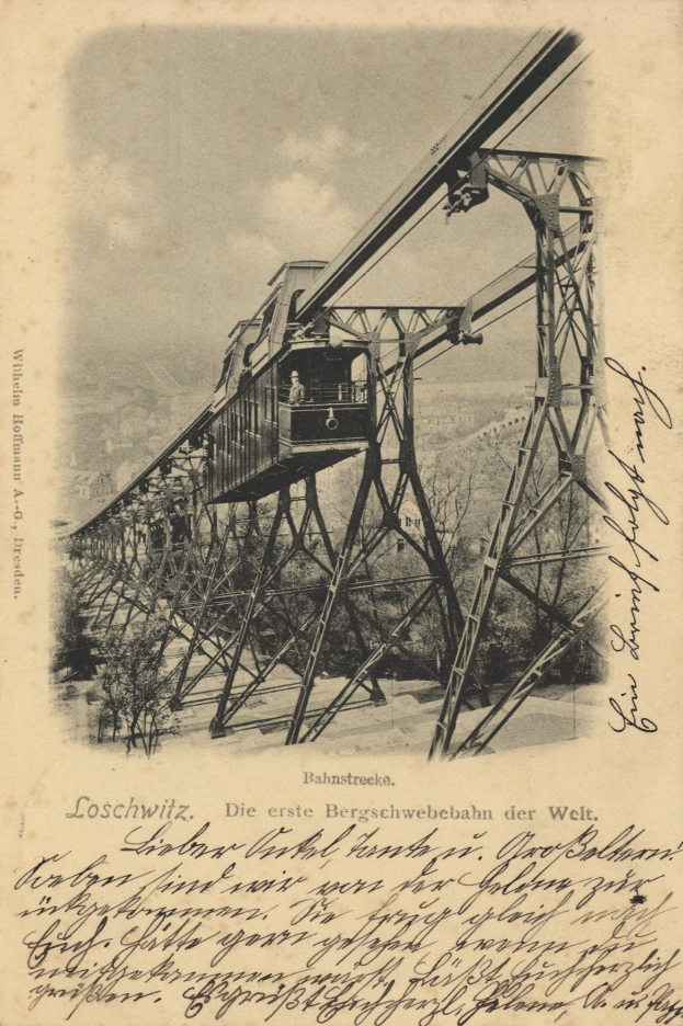 Ein altes Schwarz-Weiß-Foto einer Eisenbahnbrücke mit einem Kran, umgeben von Bäumen und einem bewölkten Himmel, mit dem Text "Bahnstrecke, die erste Eisenbahnbrücke in Deutschland" unten.