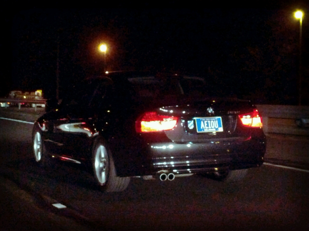Ein schwarzes Auto mit Lichtern und einer Aufschrift befindet sich in der Mitte einer Straße, mit einem schwarzen Hintergrund mit Lichtern.