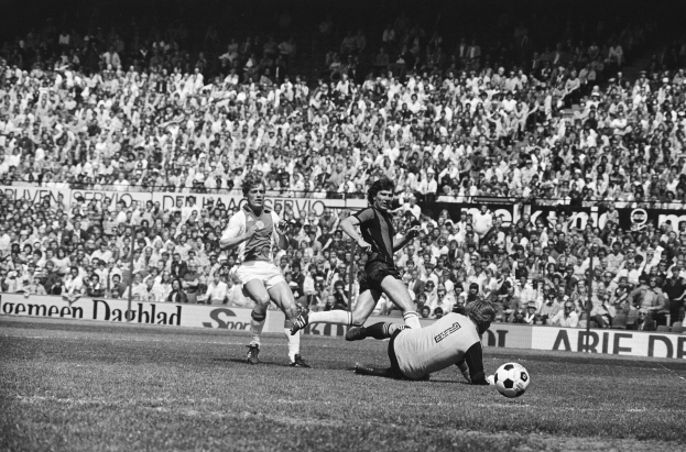 Schwarzes Foto von Männern, die auf einem Feld Fußball spielen, mit Zuschauern im Hintergrund und einer Tafel mit der Aufschrift "Bundesliga 1978-79 Ajax 1-1 Hannover 96".