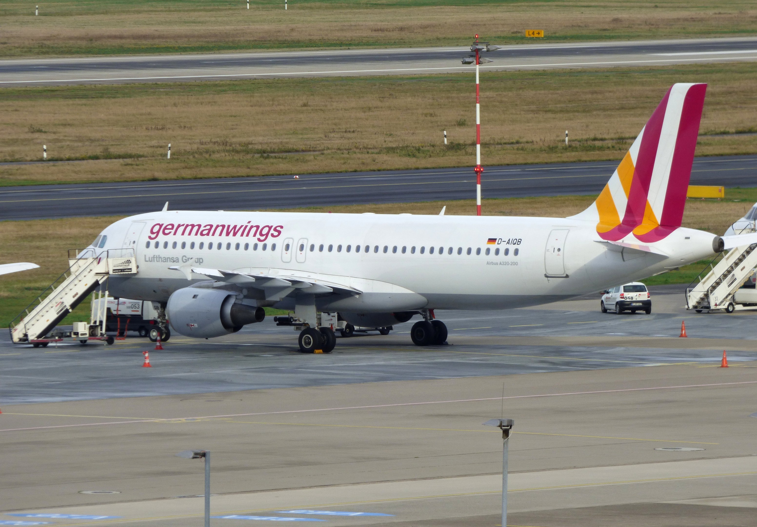 Germanwings Airbus A320-200 auf dem Frankfurt Airport geparkt mit Bodenfahrzeugen, Verkehrskegeln, Pfählen und Gras im Hintergrund.