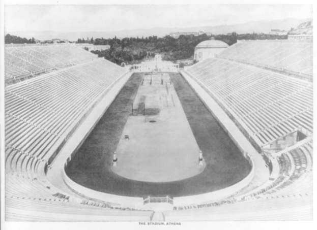 Schwarzes und weißes Foto des Olympischen Stadions in Athen, Griechenland, mit Sitzreihen, Bäumen, Gebäuden und Bergen im Hintergrund sowie Text unten.