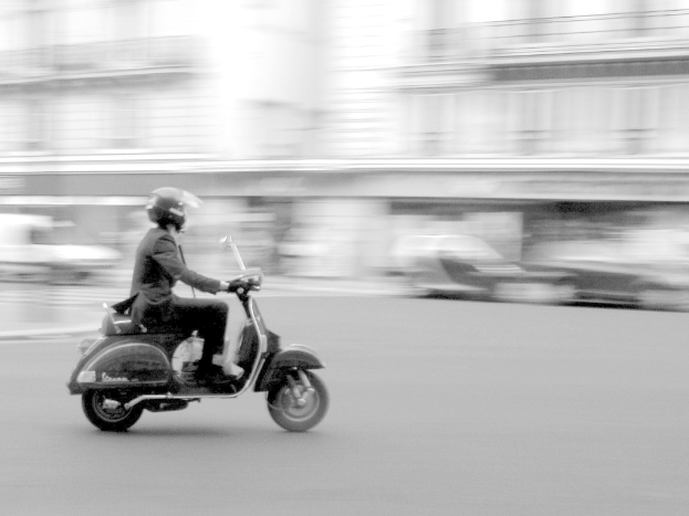 Eine Person fährt mit einem Scooter auf einer Straße.