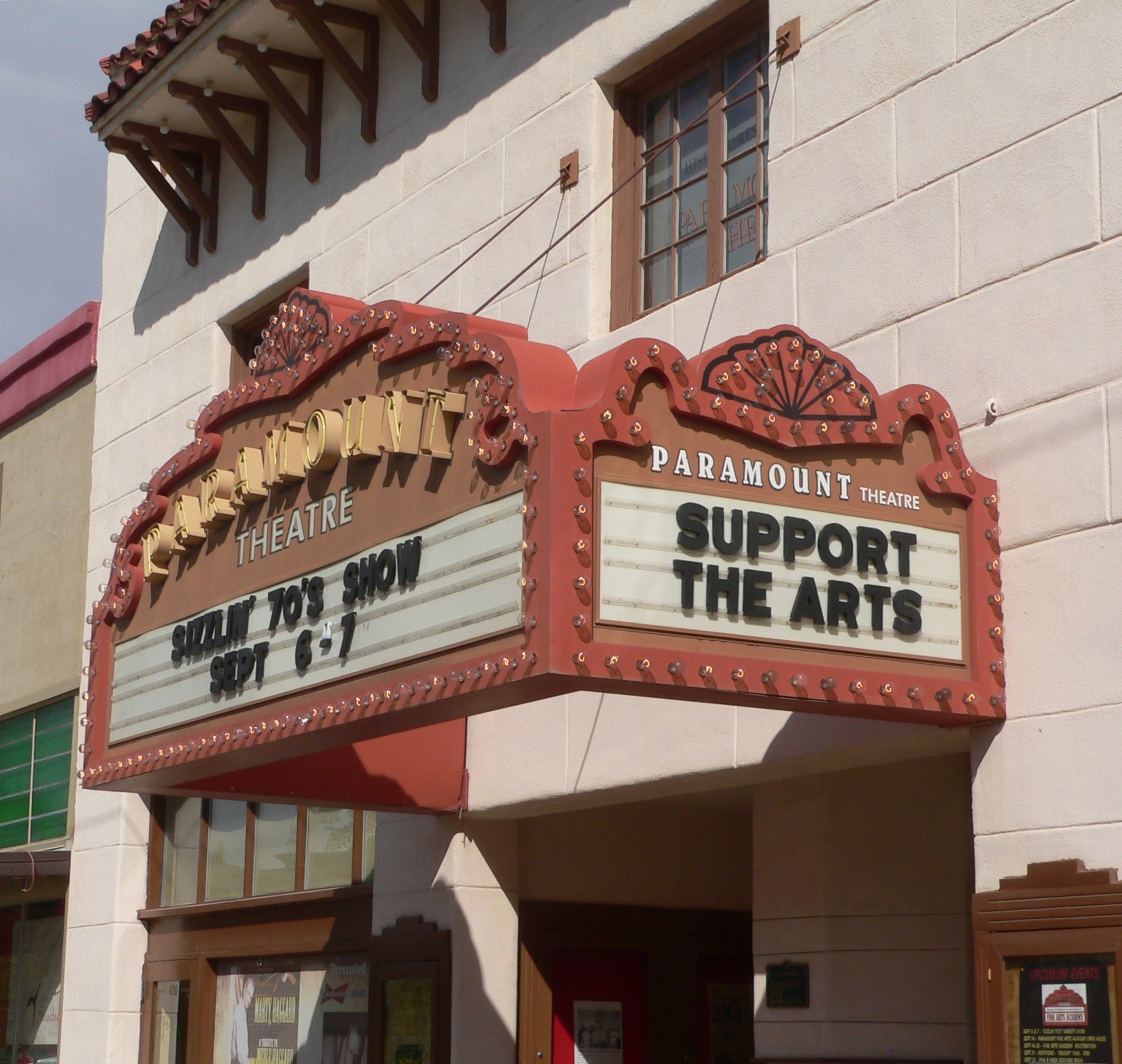 Außenansicht des Paramount Theatre in Sacramento, Kalifornien, mit Glasfenstern und -türen, einem "Support the Arts"-Schild und einem sichtbaren Himmel im Hintergrund.
