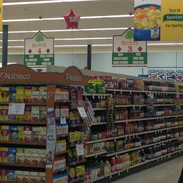 Ein Supermarktinneres mit Lebensmitteln, Deckenleuchten und Schildern.