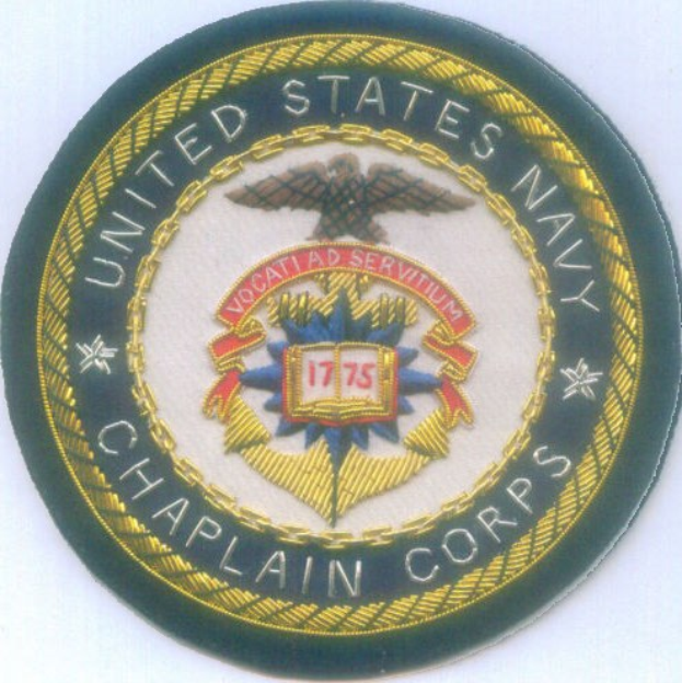 Ein rundes Abzeichen mit blauem Hintergrund und weißem Rand, auf dem der weiße Text 'United States Navy Chaplain Corps' in der Mitte steht.