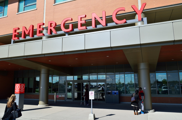 Gruppe von Menschen vor einem Notaufnahmeschlachthaus mit Glaswänden, Säulen und Beschriftungen.