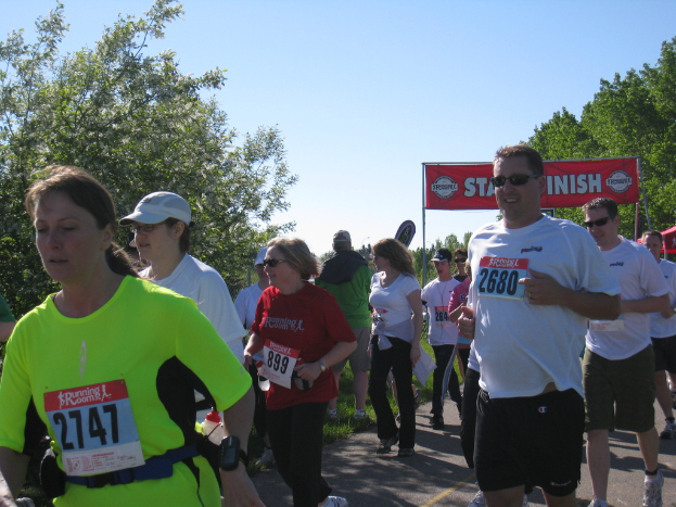Eine Gruppe von Kindern bei einem Marathonlauf, mit einem roten Banner und Bäumen im Hintergrund.