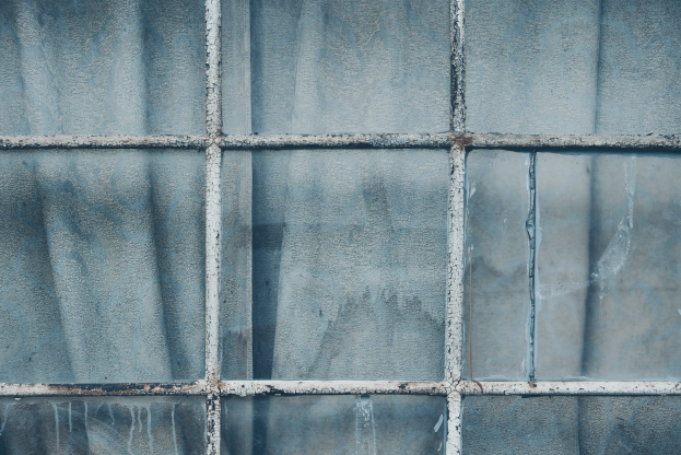 Nahaufnahme eines Glasfensters, das von einer glänzenden Frostschicht bedeckt ist.