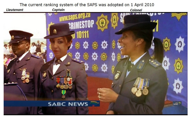 Gruppe von Menschen in Uniformen und Hüten, die vor einer Banner mit dem Text "Das aktuelle Ranglistensystem der SAP wurde am 1. April 2010 eingeführt" stehen.