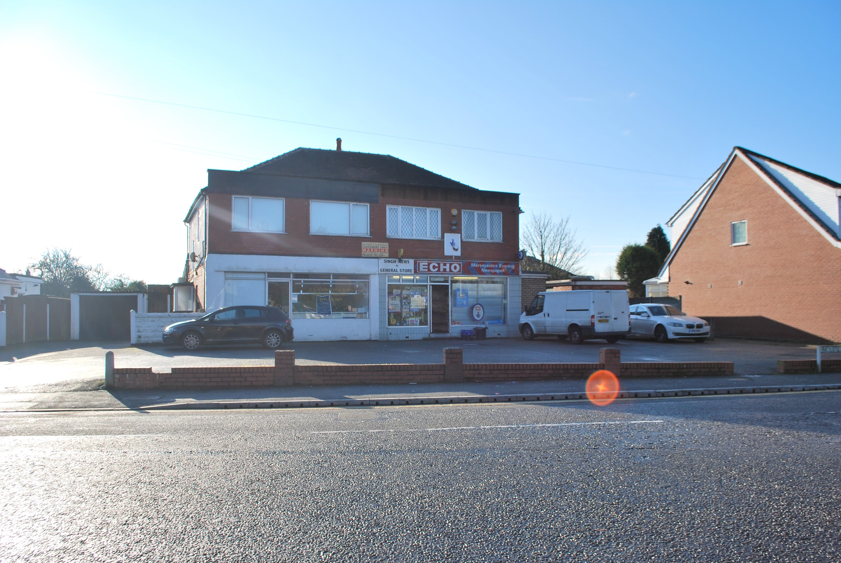 Gewerbeimmobilie zum Verkauf auf St Johns Road, Luton, Bedfordshire, mit Gebäuden, Fahrzeugen, einer Wand, Bäumen und einem bewölkten Himmel.