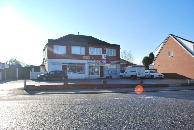 Gewerbeimmobilie zum Verkauf auf St Johns Road, Luton, Bedfordshire, mit Gebäuden, Fahrzeugen, einer Wand, Bäumen und einem bewölkten Himmel.