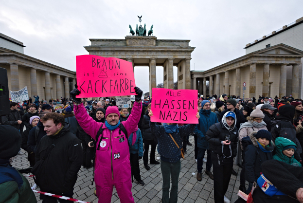 Eine Gruppe von Menschen demonstriert vor dem Reichstag in Berlin mit Schildern gegen die anti-nazistische Bewegung der deutschen Regierung.