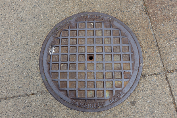 Ein rundes Metallgullideckel auf einem Stadtweg mit eingraviertem Text.