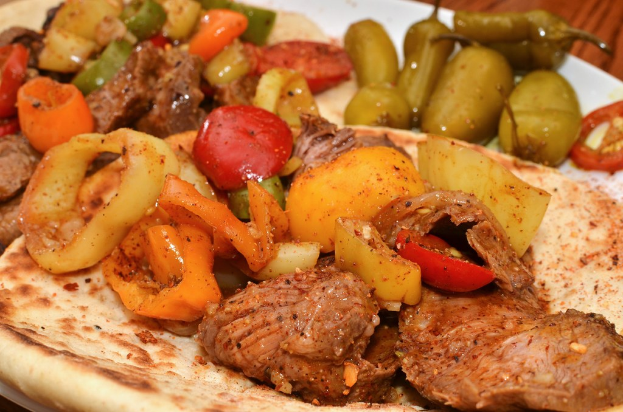 Teller mit geschnittenen Tomaten, grünen Chilischoten und Stückchen von gekochtem Huhn.