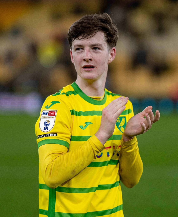 Ein junger Mann in einem gelb-grünen T-Shirt klatscht auf einem Fussballfeld und feiert ein Tor mit einem unscharfen Hintergrund.