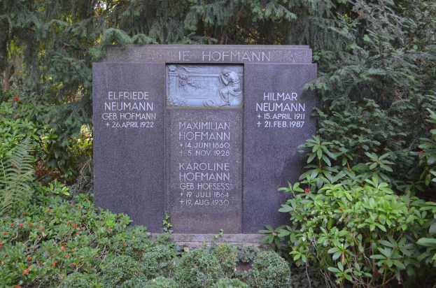 Ein Gedenkstein in einem Park umgeben von B"{a}umen und Pflanzen mit eingravierten Text, wahrscheinlich zur Erinnerung an Holocaust-Opfer.