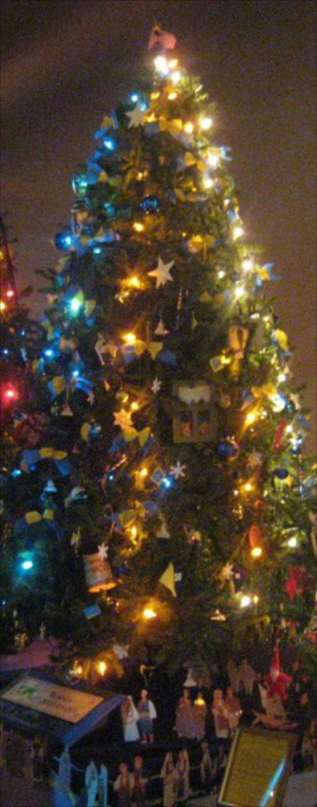 Ein geschmückter Weihnachtsbaum mit darunter platzierten Menschenfiguren.