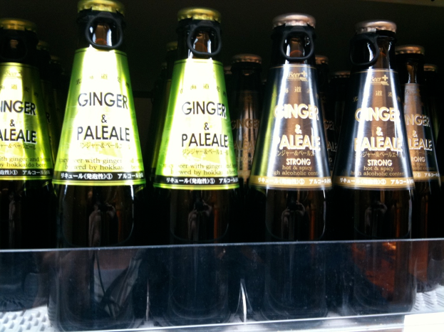 Mehrere braune Alkoholflaschen mit grünen und braunen Etiketten, einige mit Öffnerkapseln, auf einer Glasfläche plaziert.