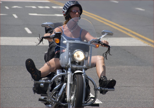 Eine Frau mit schwarzem Helm fährt ein Fahrrad auf einer Straße.