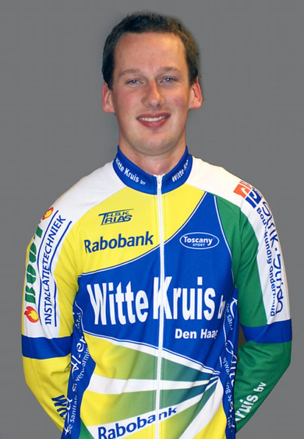 Ein männlicher Athlet posiert für ein Foto, wobei er ein Hemd trägt, auf dem mehrere Sponsorunternehmennamen angezeigt werden.