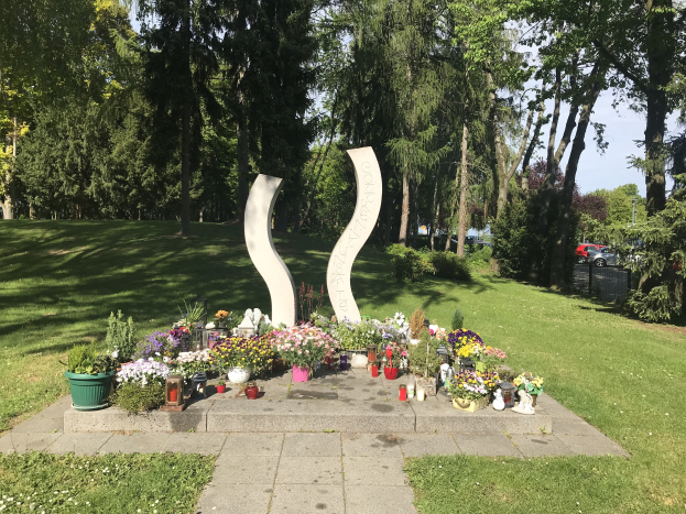 Denkmal für die Opfer des Tschernobyl-Unfalls mit Blumen, Kerzen und Grünanlage in einem Park.