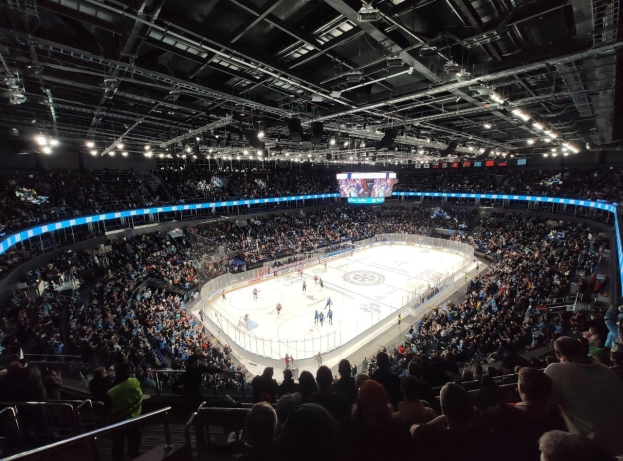 Ein Eishockeyspiel in einer großen Halle mit Zuschauern auf den Rängen und Mitarbeitern auf dem Eis, mit der O2 Arena in London.